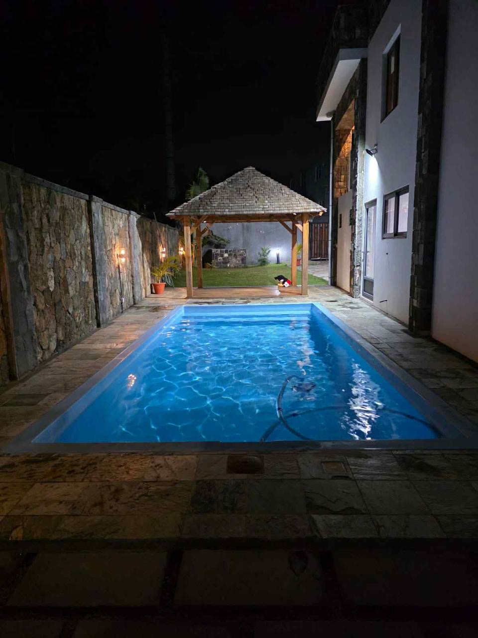 Illuminated pool, gazebo and villa exterior at night