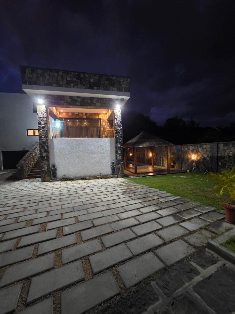 Illuminated villa exterior, courtyard and gazebo after dark