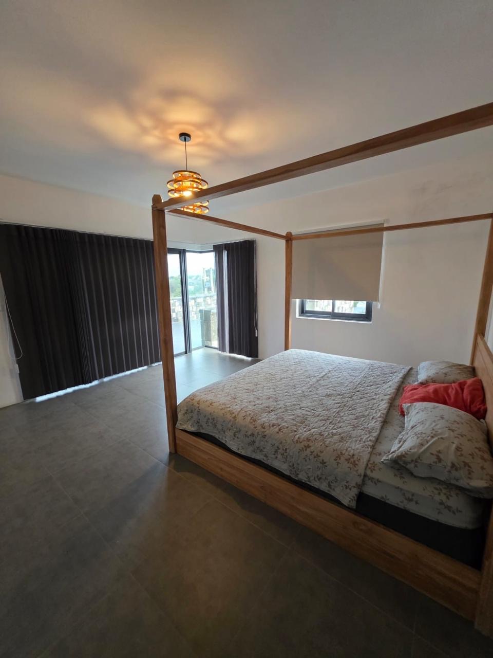 Villa bedroom with a wooden four-poster bed and glass doors